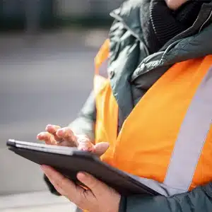 Person in Warnweste bedient ein Tablet
